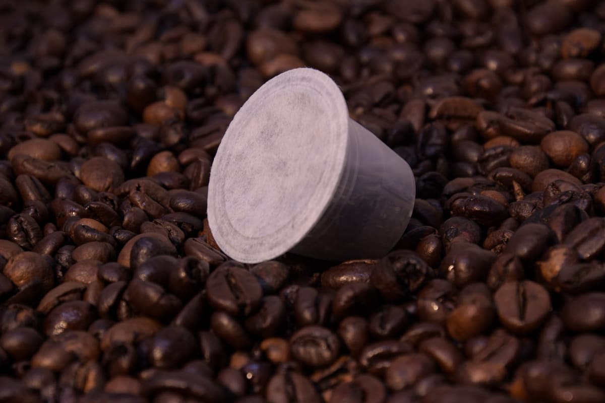 Capsula chiara appoggiata sui chicchi di caffè