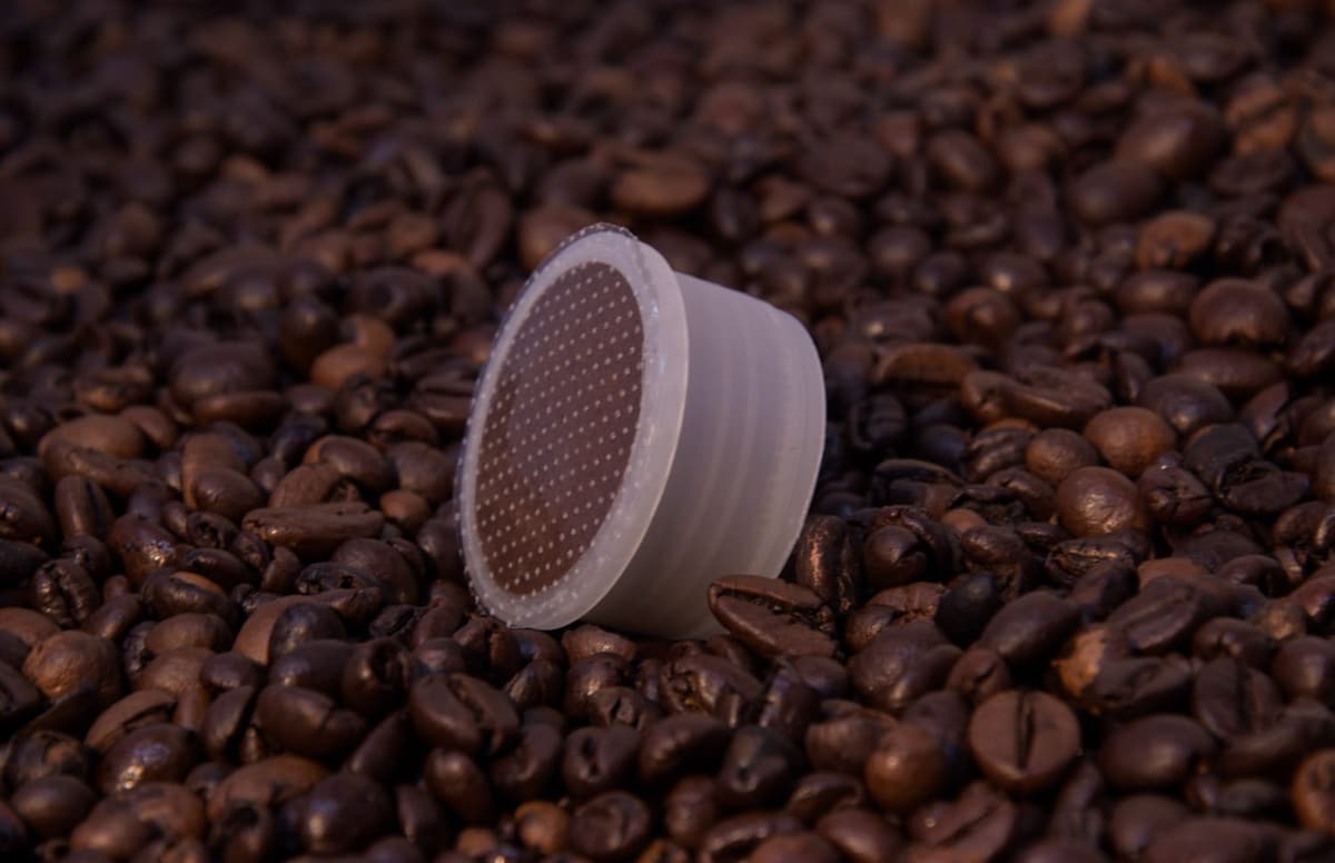 Capsula vista dall'alto con il filtro in evidenza, su chicchi di caffè