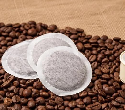 Cialde in filtro di carta e capsule compatibili appoggiate su chicchi di caffè